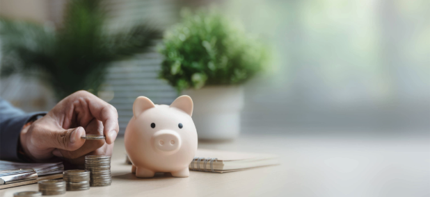 Person stacking coins next to a piggy bank representing retirement savings and long-term investing.