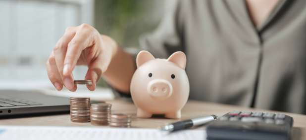 Person stacking coins next to a piggy bank while planning a retirement budget.