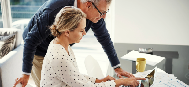 Couple reviewing retirement planning documents together at a table in a bright home office.