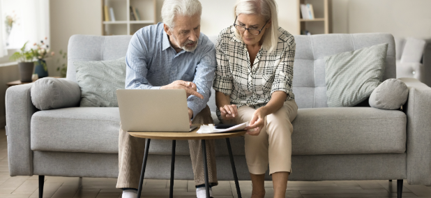 Couple reviewing retirement planning documents and discussing retirement readiness at home.